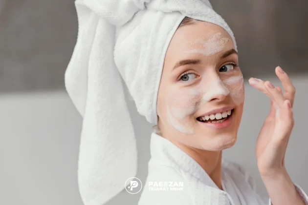 دختری که حوله دور سرش پیچیده است و صورت خود را با کف می شوید