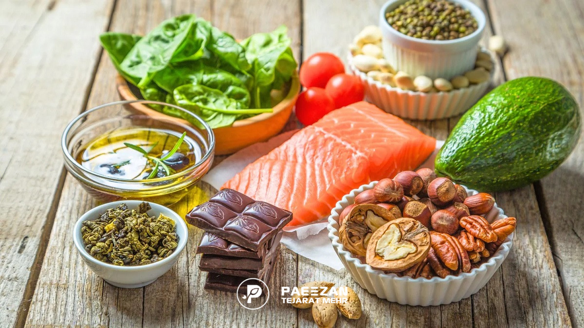 چند ماده غذایی مختلف شامل آووکادو، گردو، فندق، کاکائو، روغن، گوشت ماهی، و اسفناج و گوجه و بادام