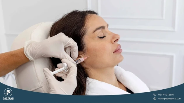 عکس دختری که روی صندلی کلینیک زیبایی نشسته است و پزشک به صورت او جوانساز پروفایلو تزریق می کند