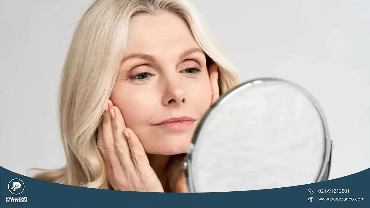 برای جوانسازی پوست صورت چه بخوریم؟ 2 یک زن که چهره های خود را در آینه می بینید و دست های خود را روی صورتش گرفته است