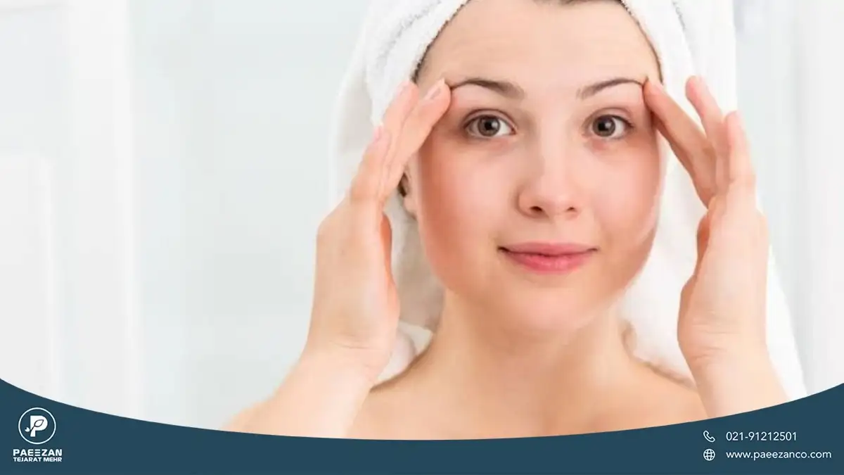 دختری که حوله دور موهای خود پیچیده است و با دو دست شقیقه خود را می کشد